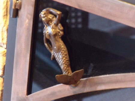 Close up view of the Mermaid on the Mariners Wife fireplace doors